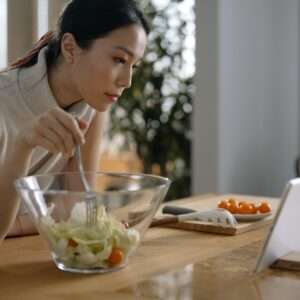 A Woman Looking at the Digital Tablet while eating his vegetable salad