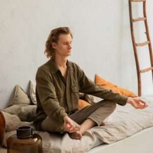 Concentrated man meditating in Lotus pose on mattress