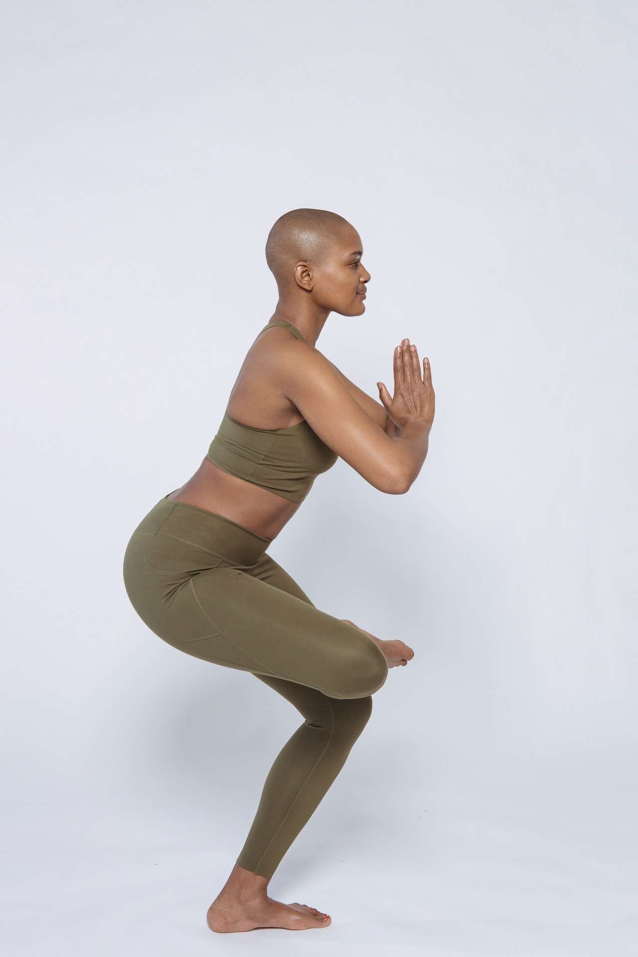 Fit black woman doing half lotus pose in studio 