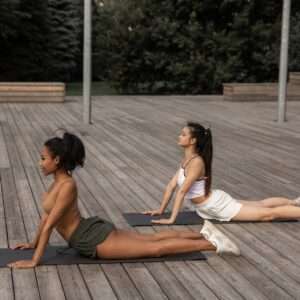Flexible women practicing Bhujangasana on mats
