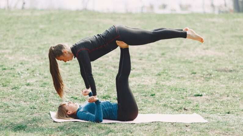 Flexible young women performing acro yoga exercise together