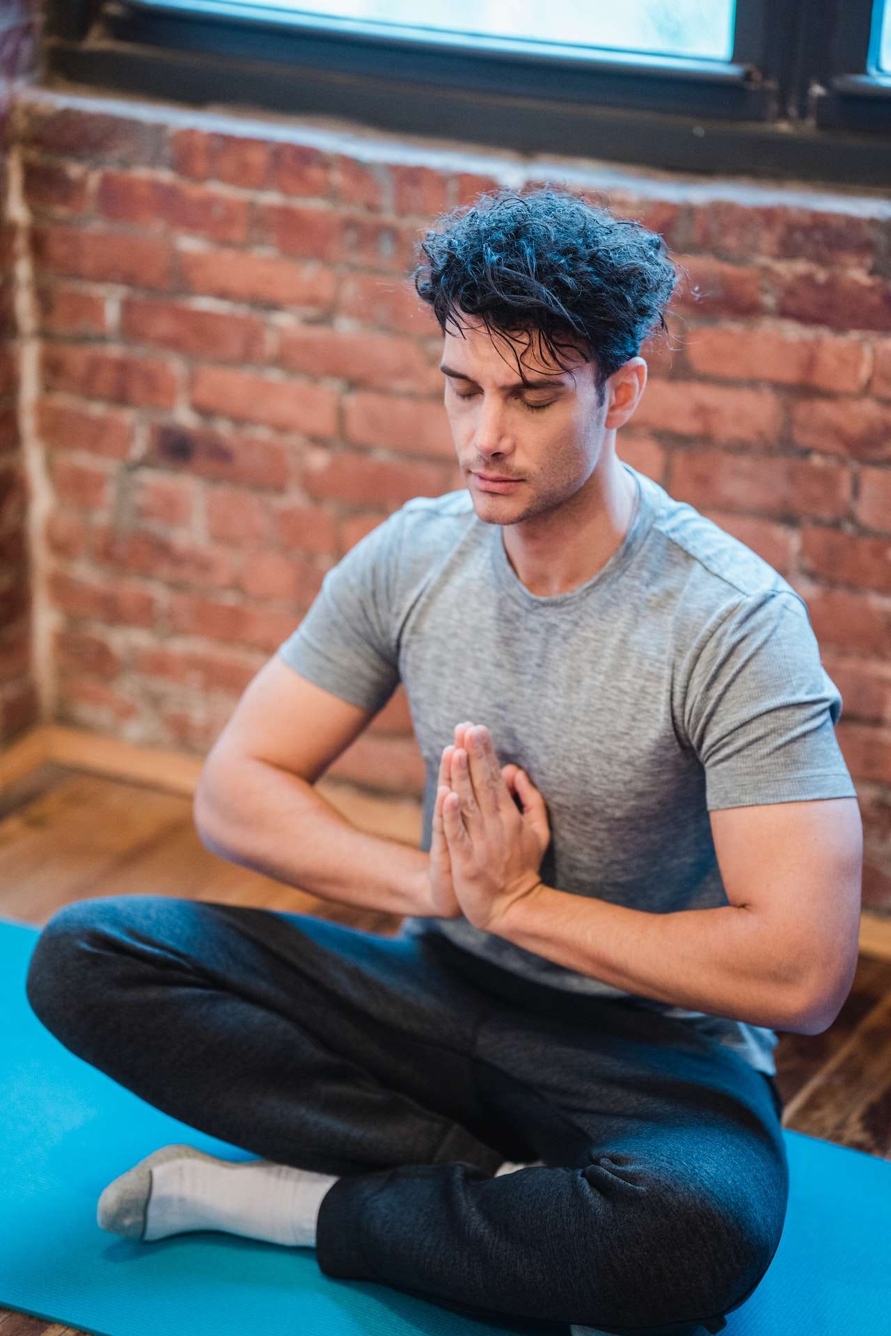 Man with hands together meditating on mat

