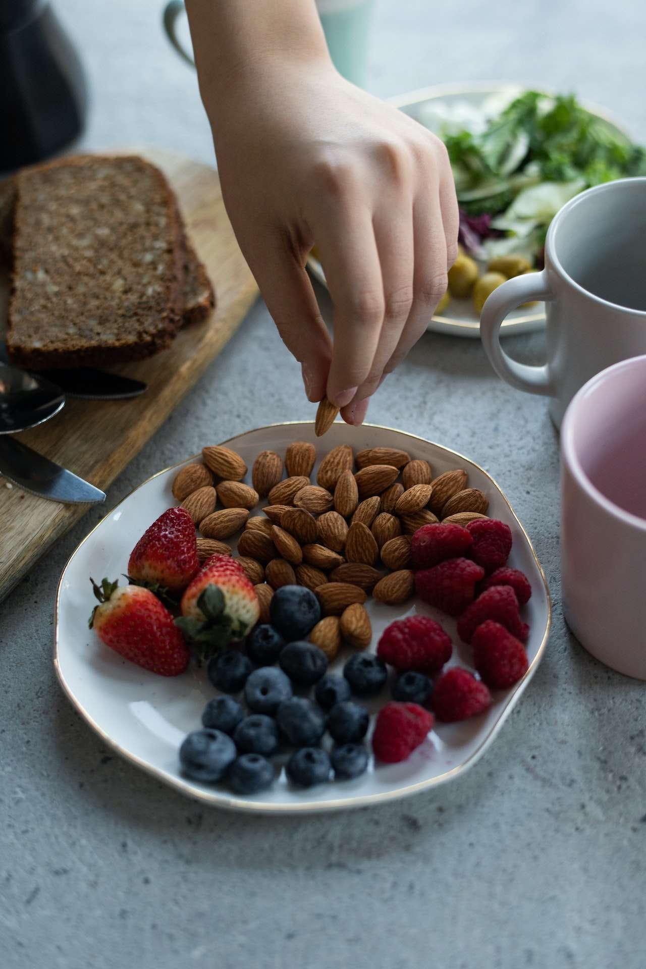 Photo Of Person Holding Almond on a plate of berries
