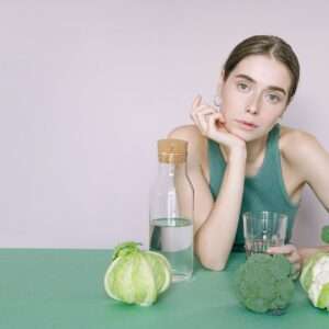 Woman in Green Tank Top Sitting on Green Table with green vegetables