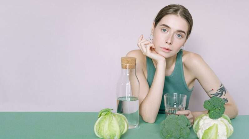 Woman in Green Tank Top Sitting on Green Table with green vegetables