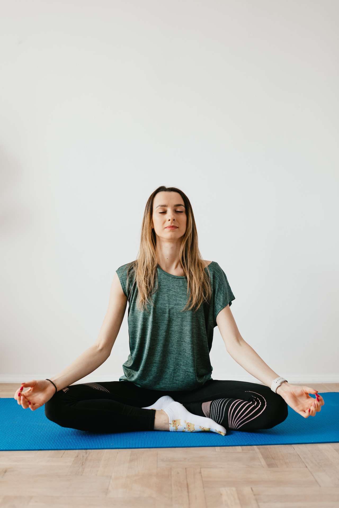 Young woman sitting in Lotus pose during meditation at home 