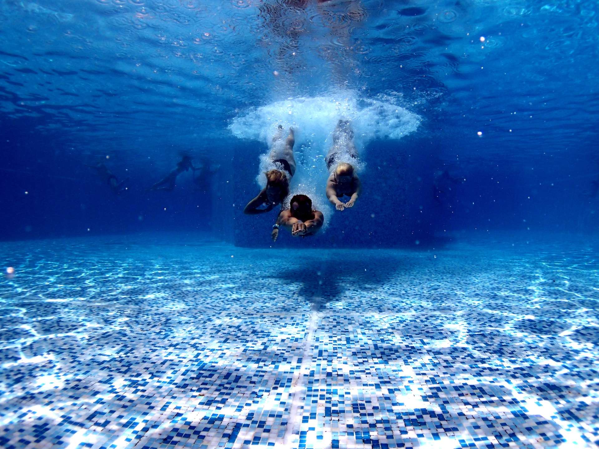 three person diving into the water