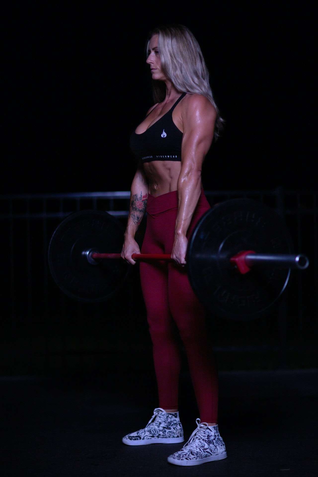 A Woman in Red and Black Sportswear Lifting Barbell
