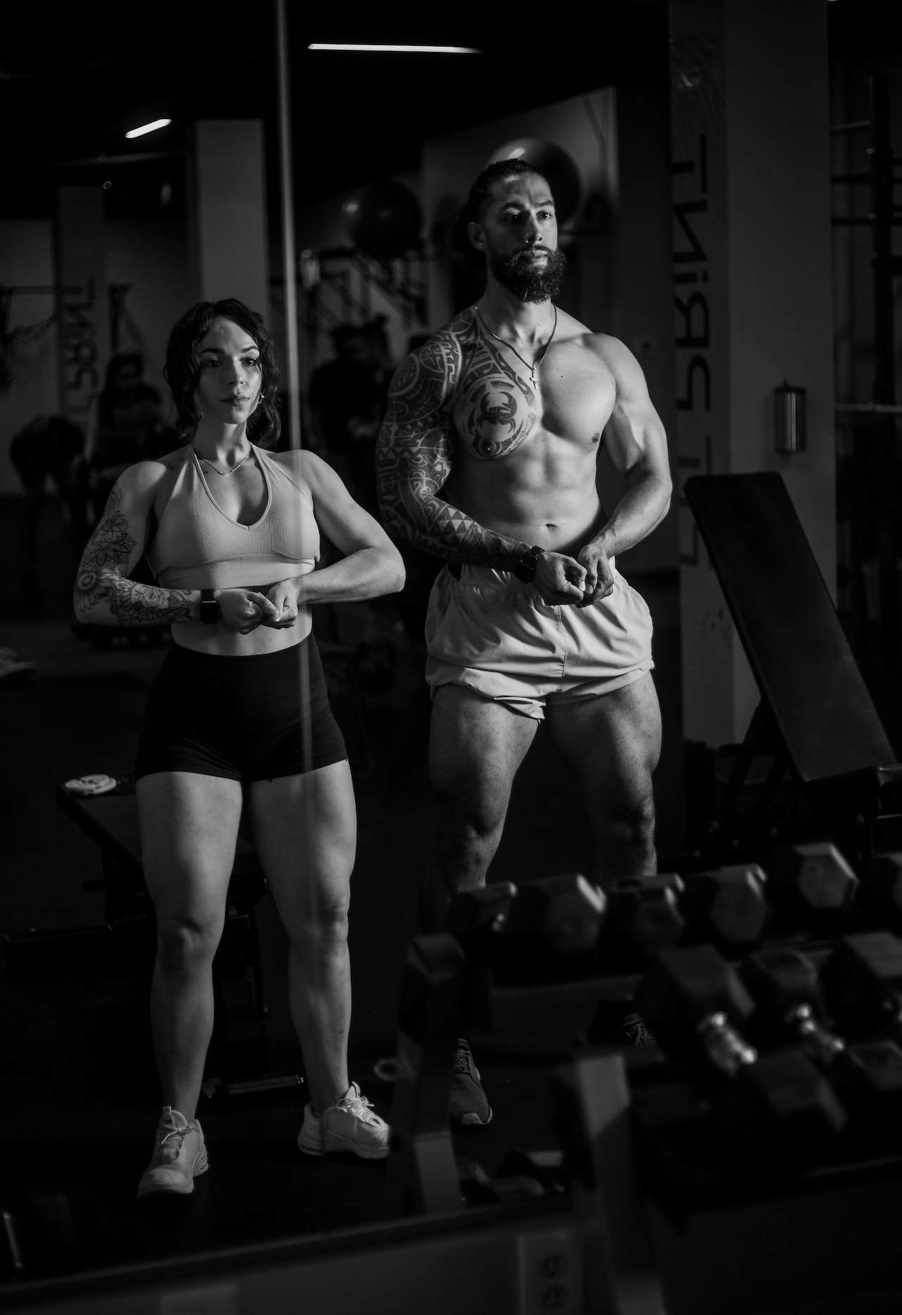 Black and White Photo of Man and Woman Exercising on Gym 