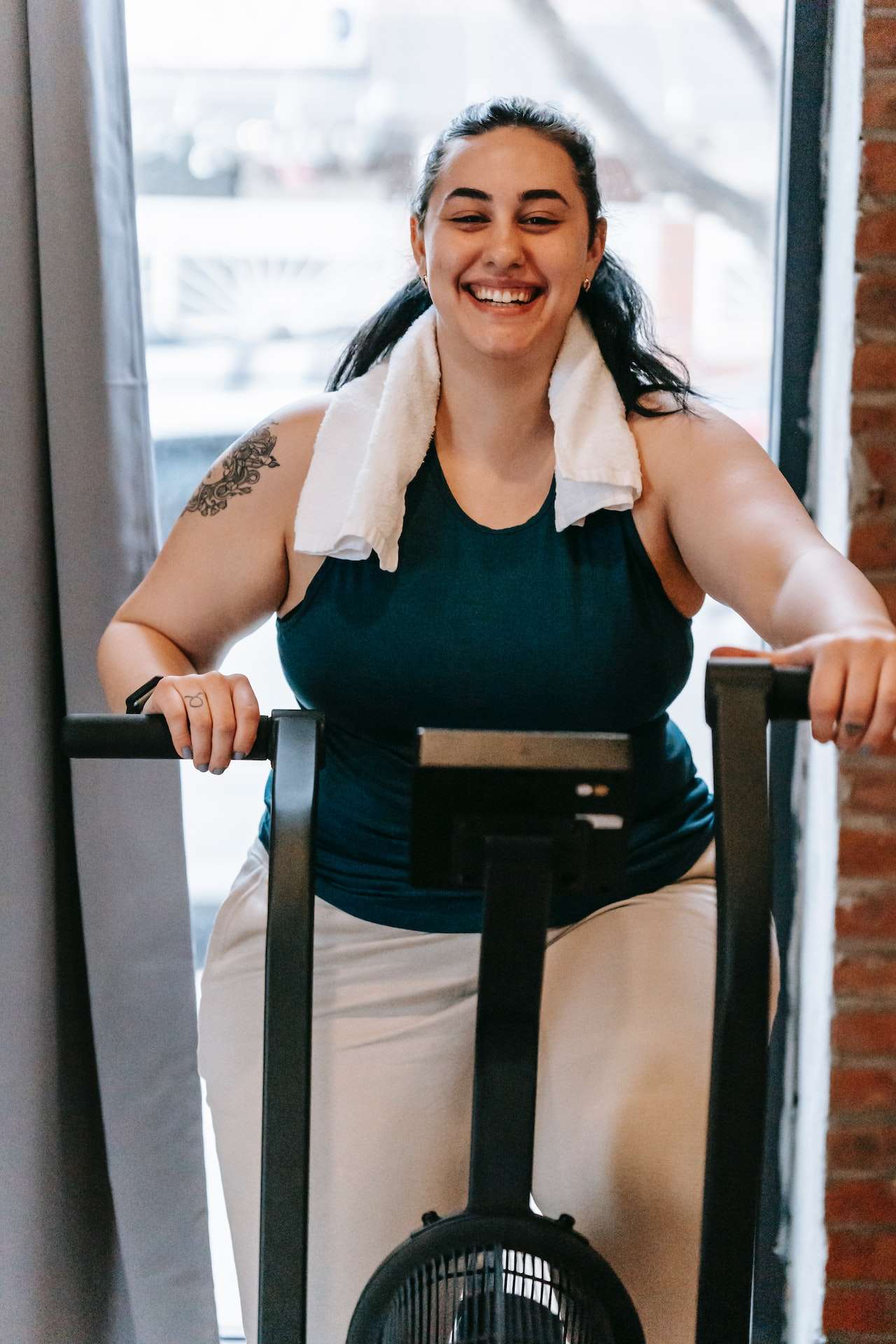 Happy overweight ethnic woman exercising on machine in gym
