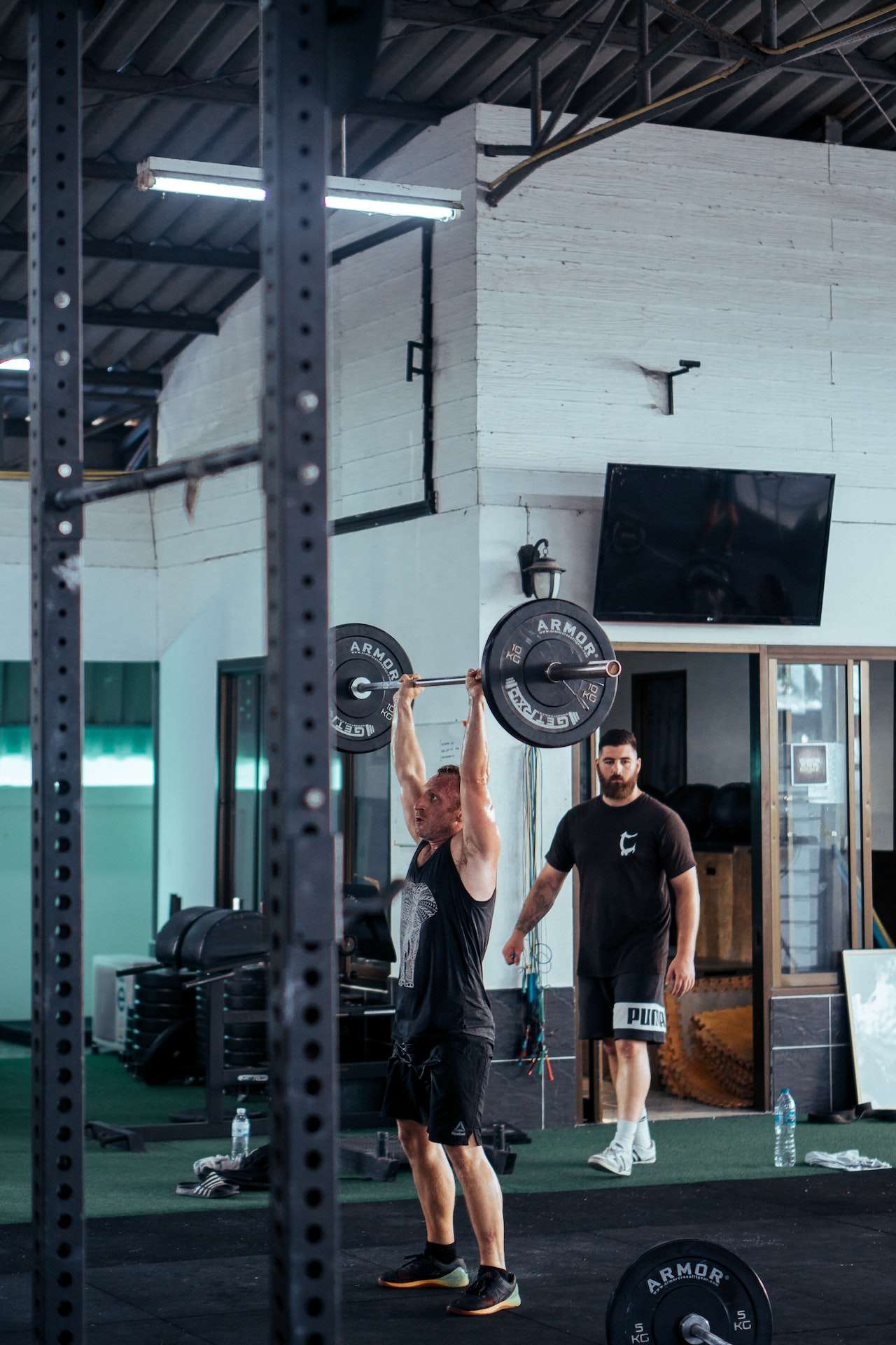 Man In Black Tank Top Lifting Barbell At The Gym 