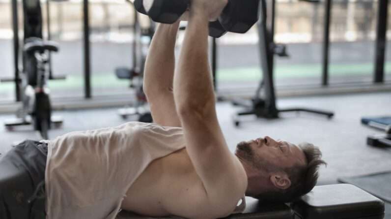 Man in White Tank Top and Grey Shorts Lifting Weights