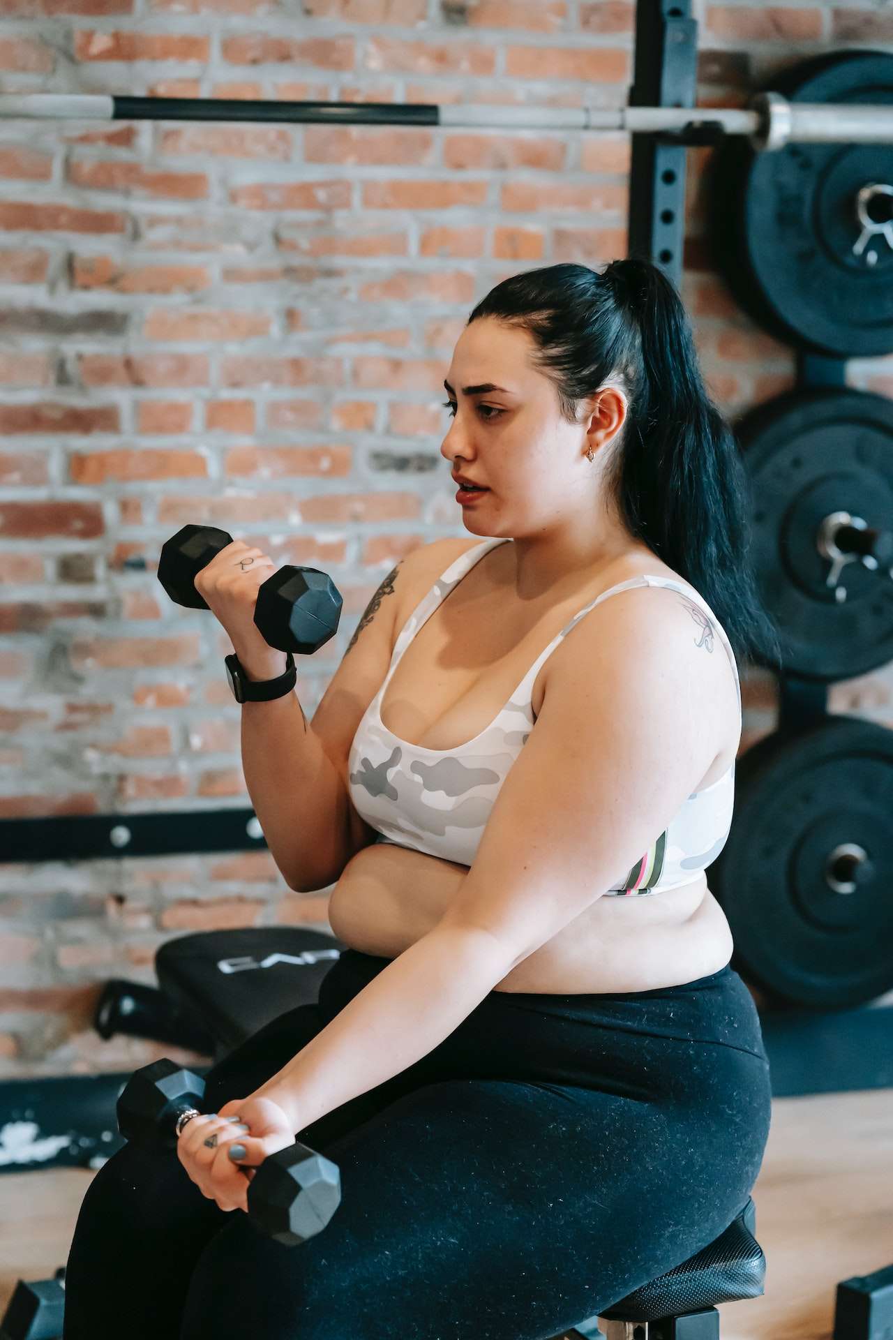 Obese woman lifting dumbbells in gym
