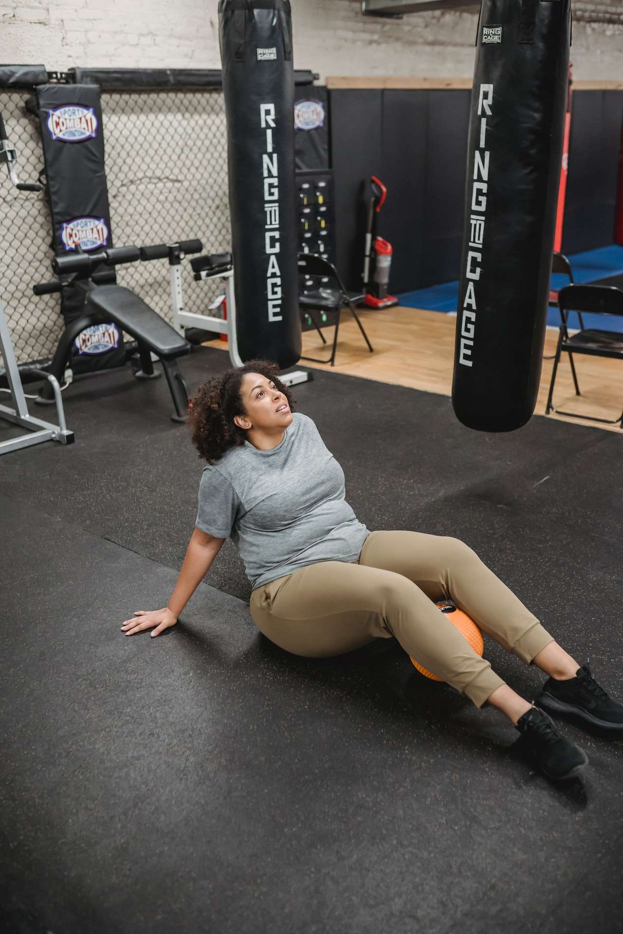 Overweight concentrated black woman exercising while rolling on ball
