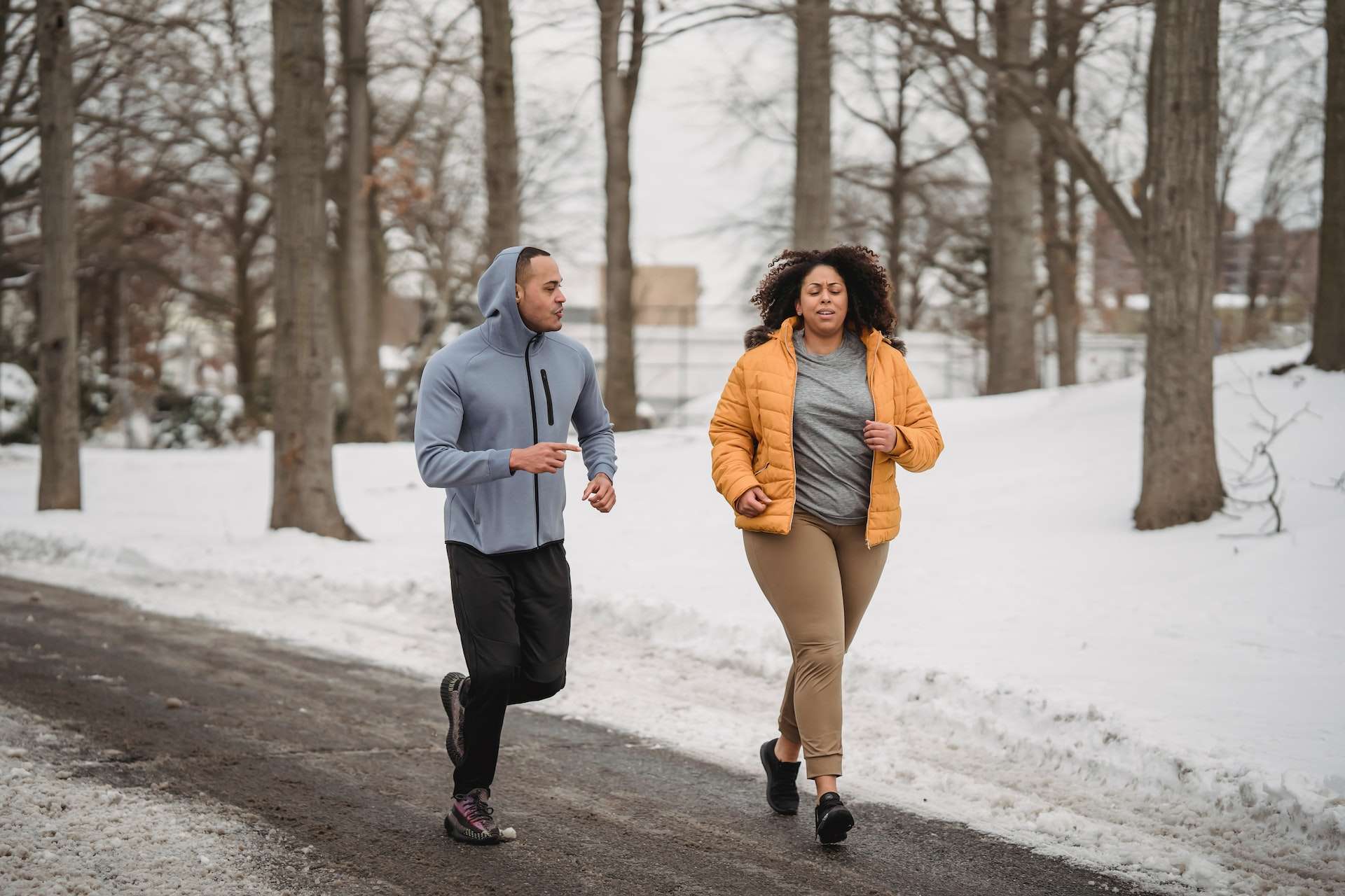 Plump black woman running with trainer in winter park