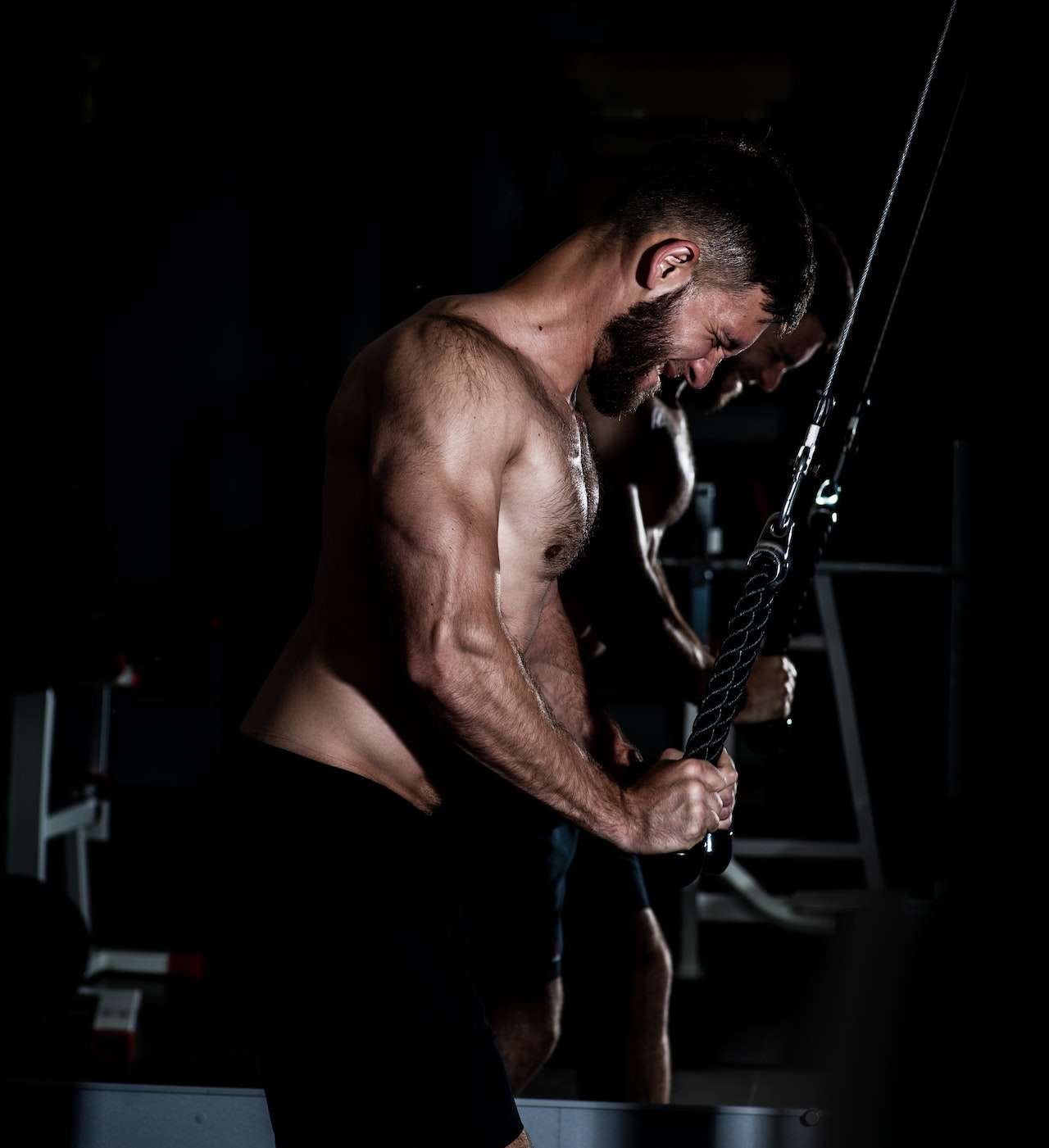Strong bodybuilder exercising with ropes triceps extension 