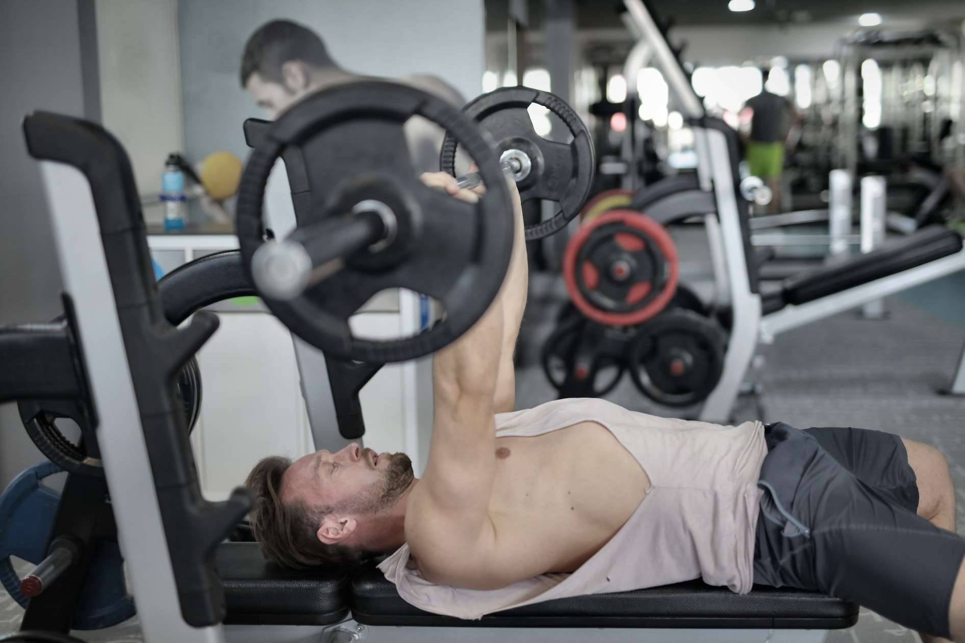 Strong sportsman doing bench press during workout in modern gym 
