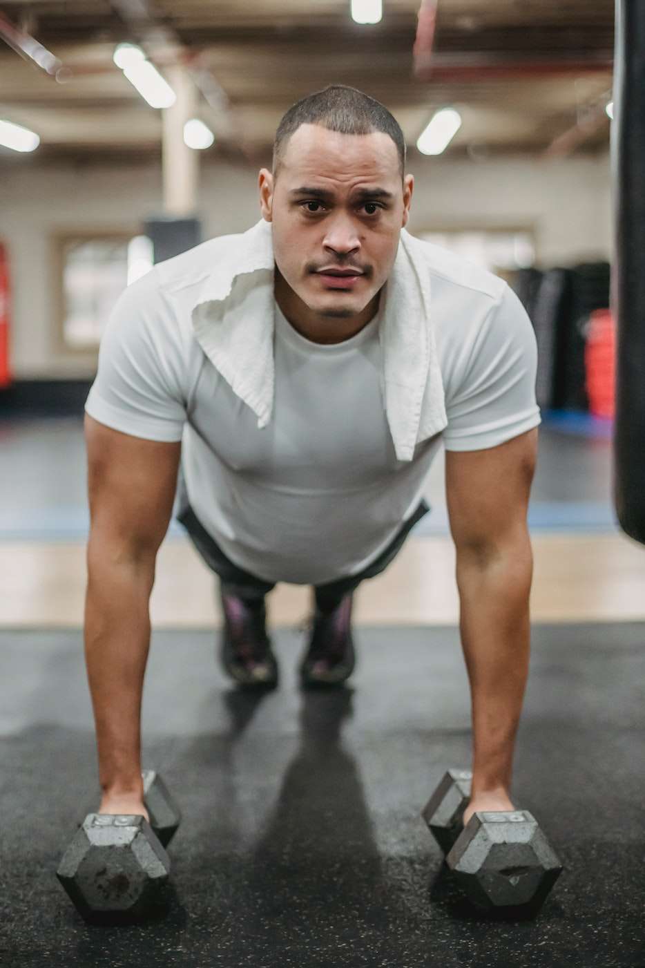 Strong sportsman performing push ups on dumbbells 