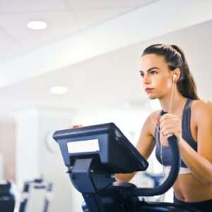Young female athlete training alone on treadmill in modern gym
